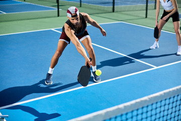 A man in a hat plays pickleball on a blue court