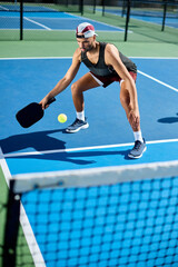 A man in a hat plays pickleball on a blue court