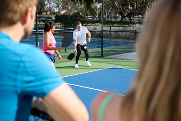 A man and a woman watch a mixed double pickleball match