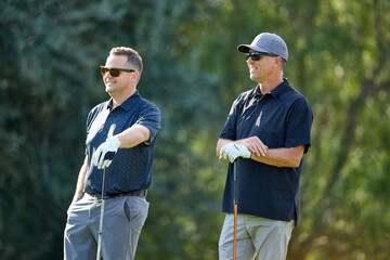 Two male golfers look on from the tee box