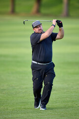 A man swings a golf club on a golfcourse