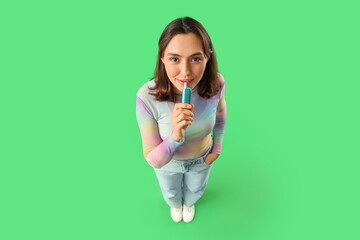 Young woman smoking electronic cigar on green background