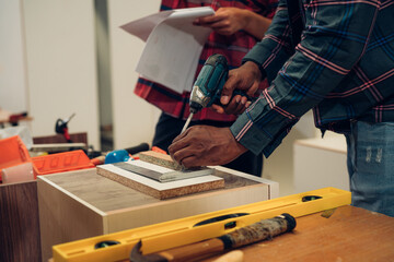 Carpenter working with hammer, meter and screw-driver on construction background.