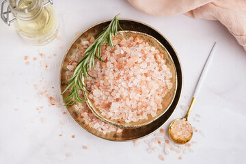 Plates with Himalayan pink salt and rosemary on white background