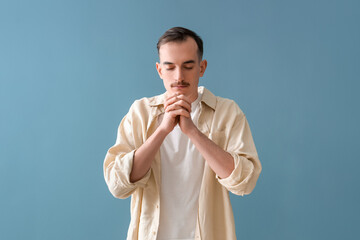 Young man praying on blue background