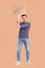 Protesting young man holding placard with word IMPEACHMENT on beige background