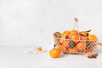 Basket of sweet mandarins with cinnamon and star anise on white wooden table