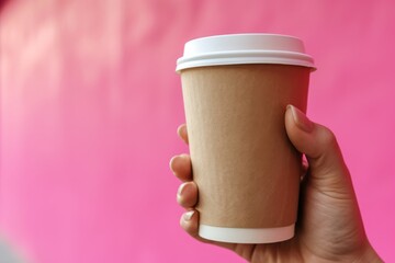 paper cup of coffee in hand on pink background