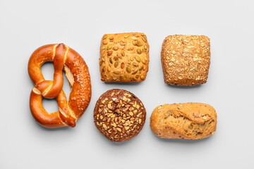 Fresh delicious buns and pretzel on white background