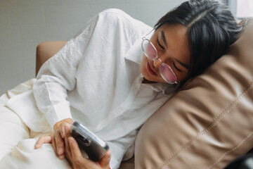 Side view of asian Thai office woman wear glasses using mobile phone while leaning and resting on...