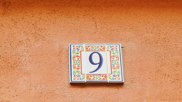 Number 9 (nine) affixed to the exterior of a building, with an elegant, vintage and traditional appearance