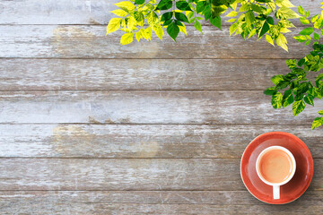 coffee cup, green leaves on wood table background with copy space. 