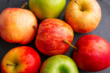delicious apples on a plate on a wooden table, bitten apple, red apple and green apple