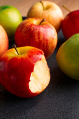 delicious apples on a plate on a wooden table, bitten apple, red apple and green apple