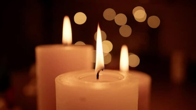 A close-up of a lit candle with a blurred background looks bright.
