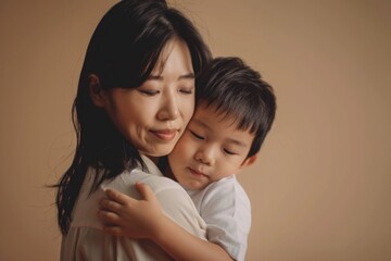 Mother hugging her son, beige background, Mother's Day celebration concept.