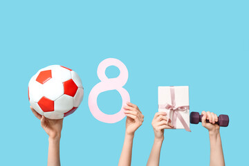 Female hands with paper figure 8, sports equipment and gift box for International Women's Day on...