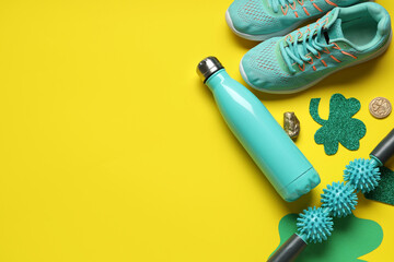 Sneakers, water bottle, body roller and decorations for St. Patrick's Day celebration on yellow background