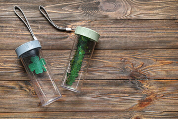 Sports bottles with clovers on wooden background. St. Patrick's Day celebration