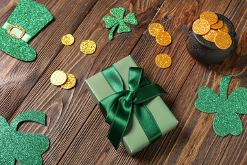 Gift box with pot of golden coins and decor for St. Patrick's Day celebration on wooden background