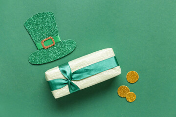 Gift box with golden coins and leprechaun hat for St. Patrick's Day celebration on green background
