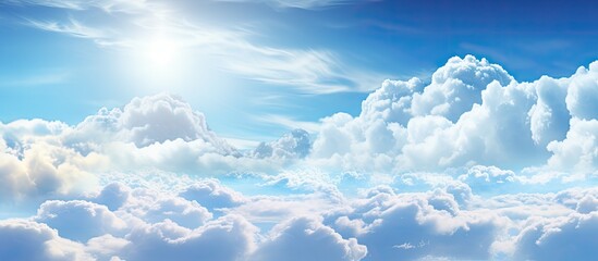 The bright sun radiates warmth across a light blue sky dotted with fluffy white and grey clouds. The suns rays illuminate the scene, creating a peaceful and serene atmosphere.