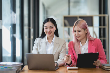 Two asian business woman working together on a project in a modern office. Teamwork and partnership concept.