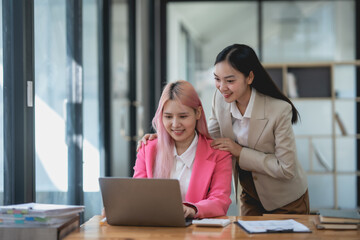 Two asian business woman working together on a project in a modern office. Teamwork and partnership concept.