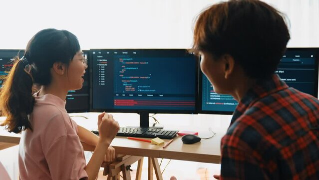 Slow motion back end software developer engineer for computer programming working together on debugging writing computing code, solving complex algorithms display on monitor in office. Burgeoning