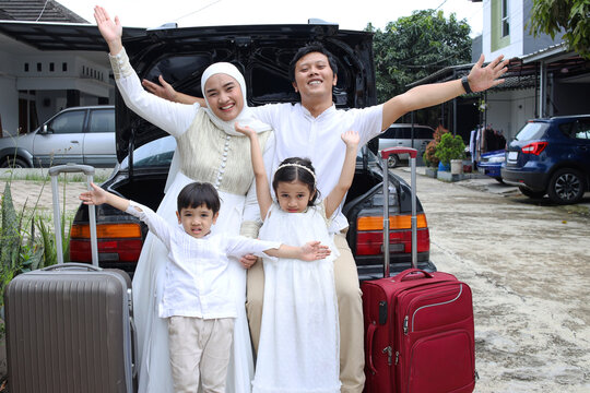 Portrait of happy muslim family sitting on the car trunk before going on mudik during Eid Mubarak moment