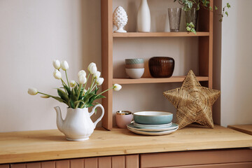 Stylish interior of a wooden Scandinavian kitchen. Fresh flowers in a vase. Ceramic plates, dishes,...