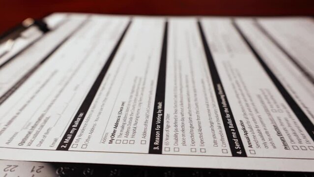 Dolly shot of voter ballot by mail application important form document on table.