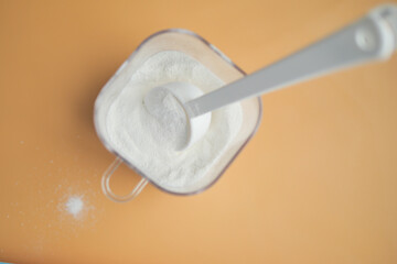 Close up of baby milk powder and spoon on tile background.
