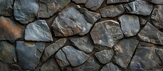 The close-up reveals a rock wall built of dark and grey rocks, creating a textured and metallic appearance. The intricate pattern showcases the natural composition and craftsmanship of the wall.