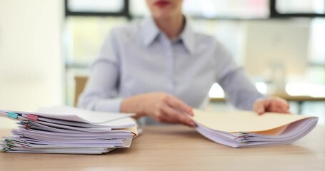 Female office worker sorts stacks of documents