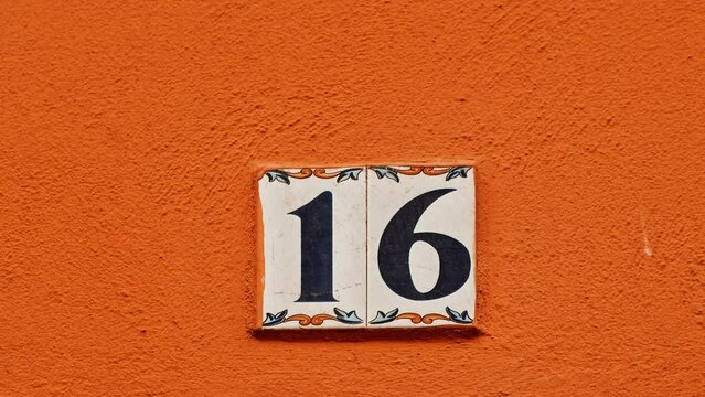 Number 16 (sixteen) affixed to the exterior of a building, with an elegant, vintage and traditional appearance