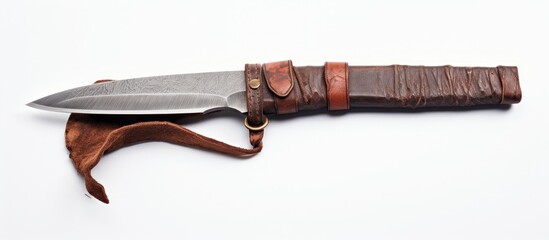 A vintage knife with a weathered blade safely enclosed in a rich brown leather sheath rests on a clean white surface. The contrast between the dark leather and the bright background highlights the