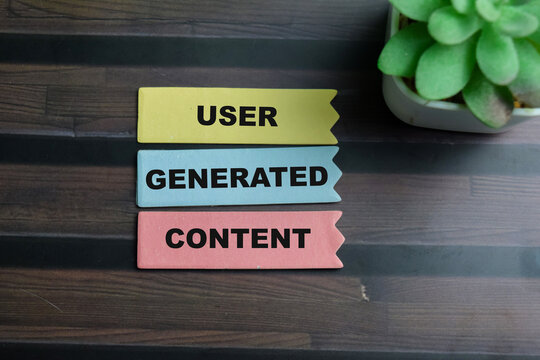Concept of User Generated Content write on sticky notes isolated on Wooden Table.