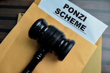 Red Handle Rubber Stamper and Ponzi Scheme text above brown envelope isolated on wooden background