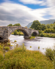 Fototapeta na wymiar Historic steep stone arch bridge crossing a river - Pont Fawr (Inigo Jones Bridge) Llanrwst North Wales