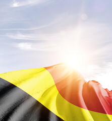 Belgium flag in waving in beautiful sky with sunlight.