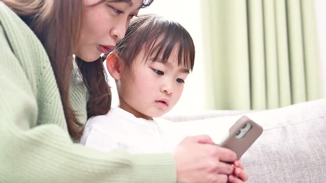 楽しくスマホを見る親子(母と娘）のイメージ　アプリや動画、ゲームを一緒に見るクローズアップの動画