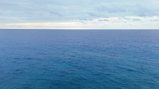 Aerial slow dolly out to deep blue majestic open ocean sea