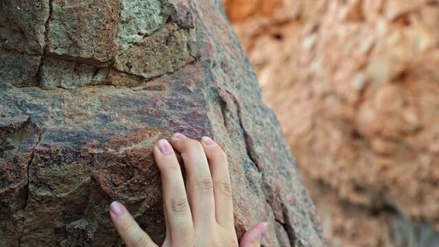 Helpless female hand reaches on the rock and slips down, falling concept