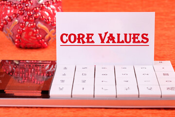 CORE VALUES word written on a white business card on a calculator on an orange background