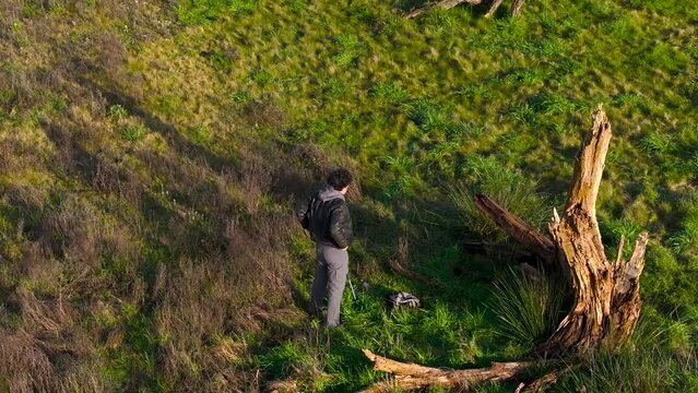 Outdoor Photographer Next To Dead Tree Wood On Rural Landscape. aerial, ascending pullback shot