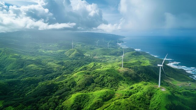 Wind turbines stand atop lush green hills with a panoramic view of the coast and sea, symbolizing sustainable energy generation. 