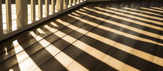 The suns rays illuminate the wooden deck of a porch, casting shadows of the fence in an abstract pattern.