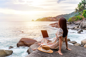 Young woman freelancer traveler working online using laptop while traveling on summer vacation,...