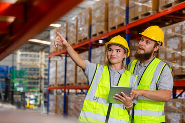 Male and Female professional worker wearing safety uniform using tablet inspect goods on shelves in warehouse. supervisor worker checklist stock inspecting product in storage for logistic.